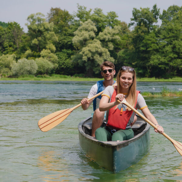 couple of explorers conoining on wild river Couple adventurous explorer friends are canoeing in a wild river surrounded by the beautiful nature
